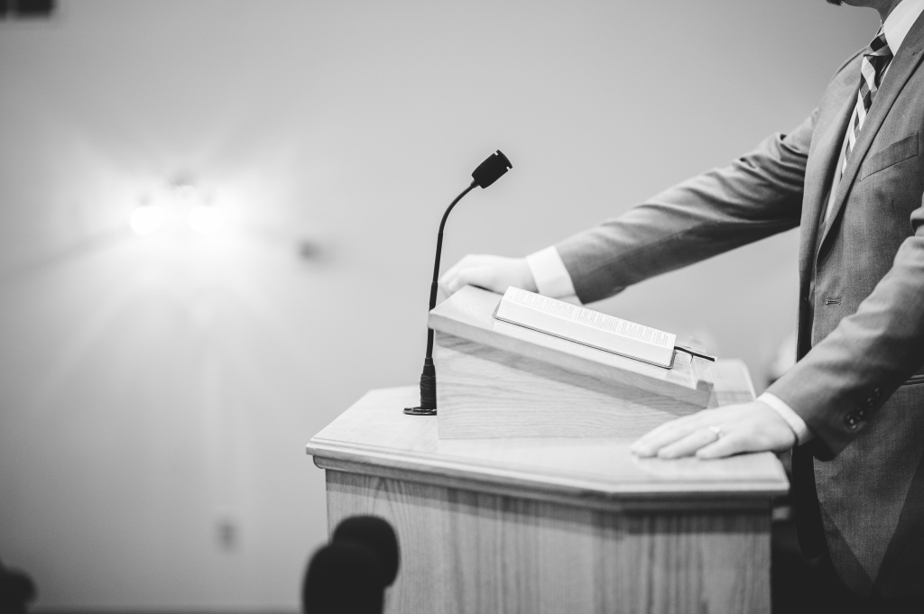 a-grayscale-shot-of-a-male-speaking-at-the-podium.jpg