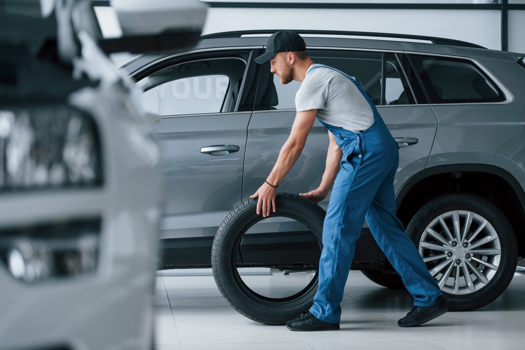 new-one-mechanic-holding-a-tire-at-the-repair-garage-replacement-of-winter-and-summer-tires-min.jpg